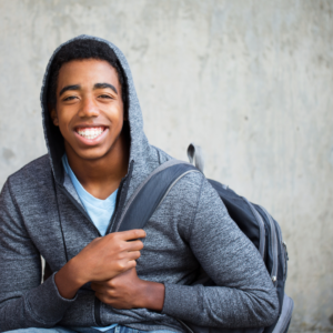 Male, African American teenager with backpack, smiling at the camera.
